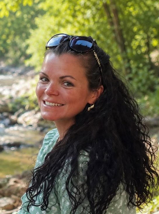 Amy smiling for a photograph in the woods.